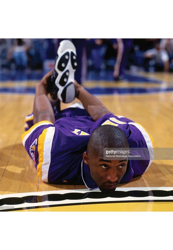 Kobe Bryant in white Lakers warmup jacket looks on before a pre